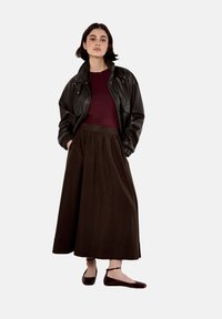 Mustat nahkabomberitakki, viininpunainen slim fit -paita, pitkä ruskea hame ja viininpunaiset matalat kengät, joissa on sileä pinta ja rento istuvuus.