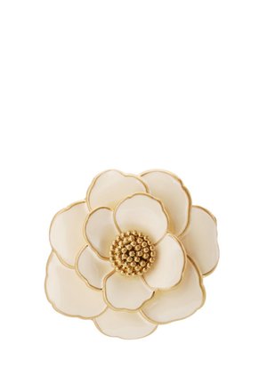 Broche florale blanche avec finition dorée, présentant des pétales superposés et un centre texturé composé de petites perles dorées. Forme circulaire, texture lisse.