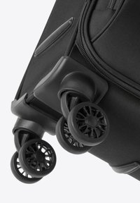 Nahaufnahme einer schwarzen Rollreisetasche, die drei strapazierfähige Rollen mit einem strukturierten Design und einem stabilen Stoffbezug zeigt.