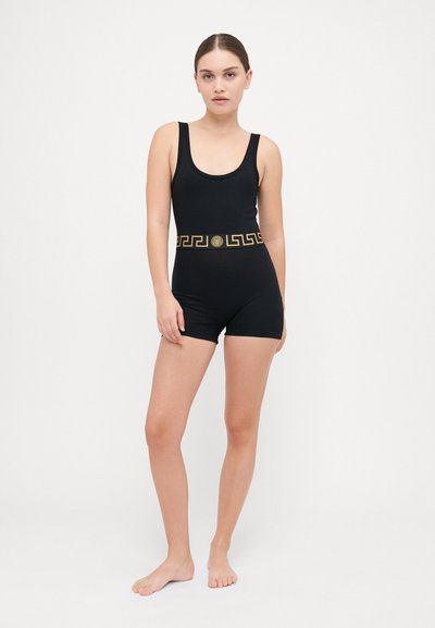 Body nero con scollo a cuore, forma aderente e motivo geometrico dorato lungo la vita. Tessuto morbido e elasticizzato, design minimalista.