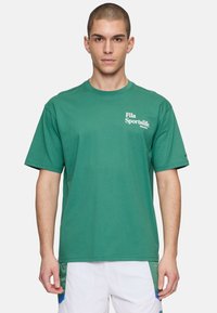 Camiseta de algodón verde con mangas cortas, cuello redondo y el logo "Fila Sportslife" impreso en la parte frontal.