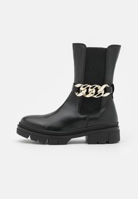 Bottine noire en cuir avec des panneaux latéraux élastiques et une semelle épaisse. Présente un accent en chaîne dor�ée autour de la cheville pour un détail supplémentaire.