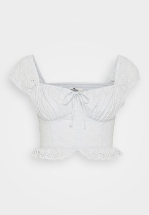 Fehér, rövidített top puffos ujjal, virágmintás hímzéssel, összegyűrt nyakkivágással és húzózsinórral, valamint fodros alsó szegéllyel.