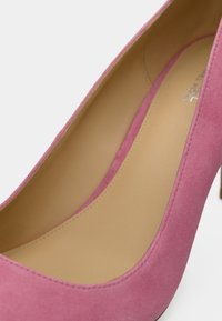 Vaaleanpunainen mokkainen korkokenkä, jossa on pyöreä kärki ja sileä beige sisävuori. Korko on kapeutettu ja keskikorkea.