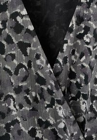 Šedá a černá látka s leopardím potiskem, s jemnou texturou a sklady podél okrajů, vytvářející vrstvený vzhled.