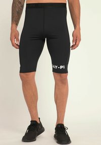 Shorts de sport noirs en tissu extensible, avec un design ajusté, un logo réfléchissant sur la jambe gauche et une taille élastique.