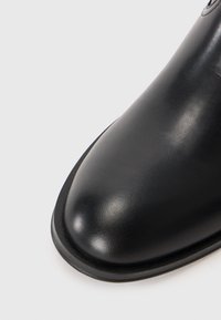 Čierne kožené oblekové topánky s oblečeným špičatým nosom, elegantným dizajnom, hladkou textúrou a jemným leskom, s tenkou čiernou podrážkou.