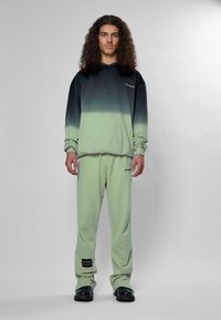 Ombre hoodie pāriet no tumši zaļas līdz gaiši zaļai; tam ir priekšējā kabata. Atbilstošas gaiši zaļas bikses ar logo uz lejas.