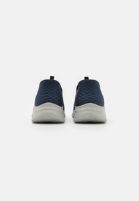 Scarpe slip-on navy con tomaia testurizzata, dotate di una suola bianca imbottita e di un tab sul tallone per facilitare l'indossamento.