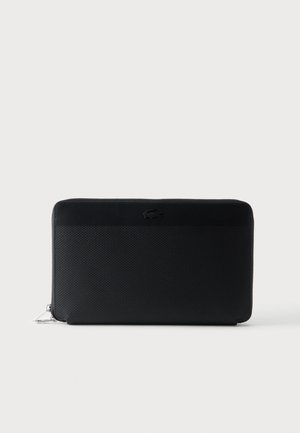 Portefeuille noir texturé avec fermeture éclair tout autour, bande supérieure en cuir lisse et logo crocodile embossé à l'avant.