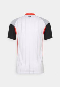Chemise de sport blanche avec de fines rayures verticales grises, manches courtes noires et grises, et accents rouges le long des côtés et du col, vue de dos.