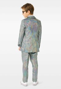 Erinevatest värvidest ruuduline pükskostüüm läikivas materjalis, millel on täpselt sobiv pintsak ja sobivad püksid, mida täiustavad valged tossud.