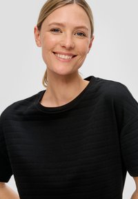 Zwart shirt met korte mouwen, voorzien van een gestructureerd patroon en een ronde hals, gemaakt van een zachte stof, met een losse pasvorm.