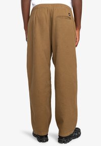 Bruine, relaxed-fit broek gemaakt van zacht materiaal met een elastische tailleband, voorzien van een achterzak, geschikt voor casual draag.