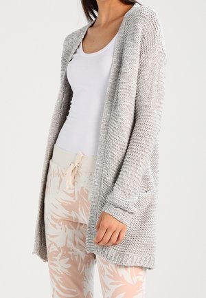 Cardigan lavorato a maglia grigio chiaro con apertura frontale, maniche lunghe e due tasche anteriori. Tessuto testurizzato e dettaglio a costine sull'orlo. Abbinato a pantaloni con motivo.