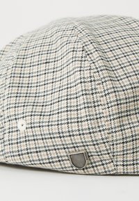 Pet met een geruit patroon in beige, grijs en zwart. Gemaakt van textuurstof met een logo-label en ventilatiegaten voor ademend vermogen.