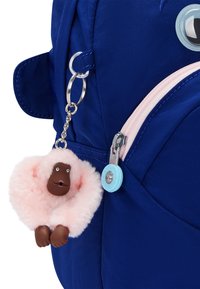 Zaino blu con una tasca con zip rosa; presenta un portachiavi a forma di scimmia pelosa rosa e un tirante della zip di colore azzurro con il testo "Kipling".