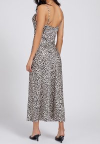 Sukienka midi w wzór panterki z cienkimi ramiączkami, z dopasowanym górą i zwiewnym dołem. Wykonana z gładkiego materiału, ma dekolt z tyłu.