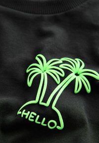 Sort stof med to neongrønne palmer og ordet "HELLO" tegnet op under dem.