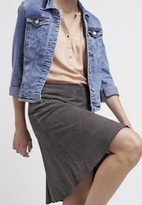 Veste en denim bleu clair avec des détails de boutons, associée à une jupe en daim gris doux avec un ourlet évasé et une texture lisse.