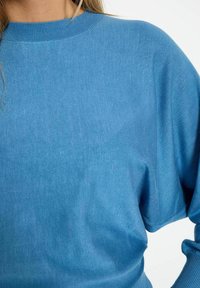Maglione a maglia azzurro chiaro con scollo rotondo, maniche ampie e una trama liscia. Presenta un sottile motivo a coste nel colletto.