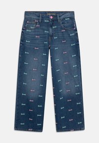 Mørkeblå denimjeans med brede ben, prydet med flerfarvede "Guess" logoer trykt i pink og grøn.
