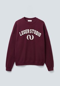 Burgunderfarget genser med rund hals og hvit "LEGERSTUDIO" tekst samt buet logo på fronten, med ribbede mansjetter og nederkant, vist på ensfarget bakgrunn.