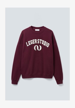 Sweatshirt crewneck bordeaux avec le texte blanc "LEGERSTUDIO" et logo courbé sur le devant, avec des poignets et un ourlet côtelés, présenté sur fond uni.
