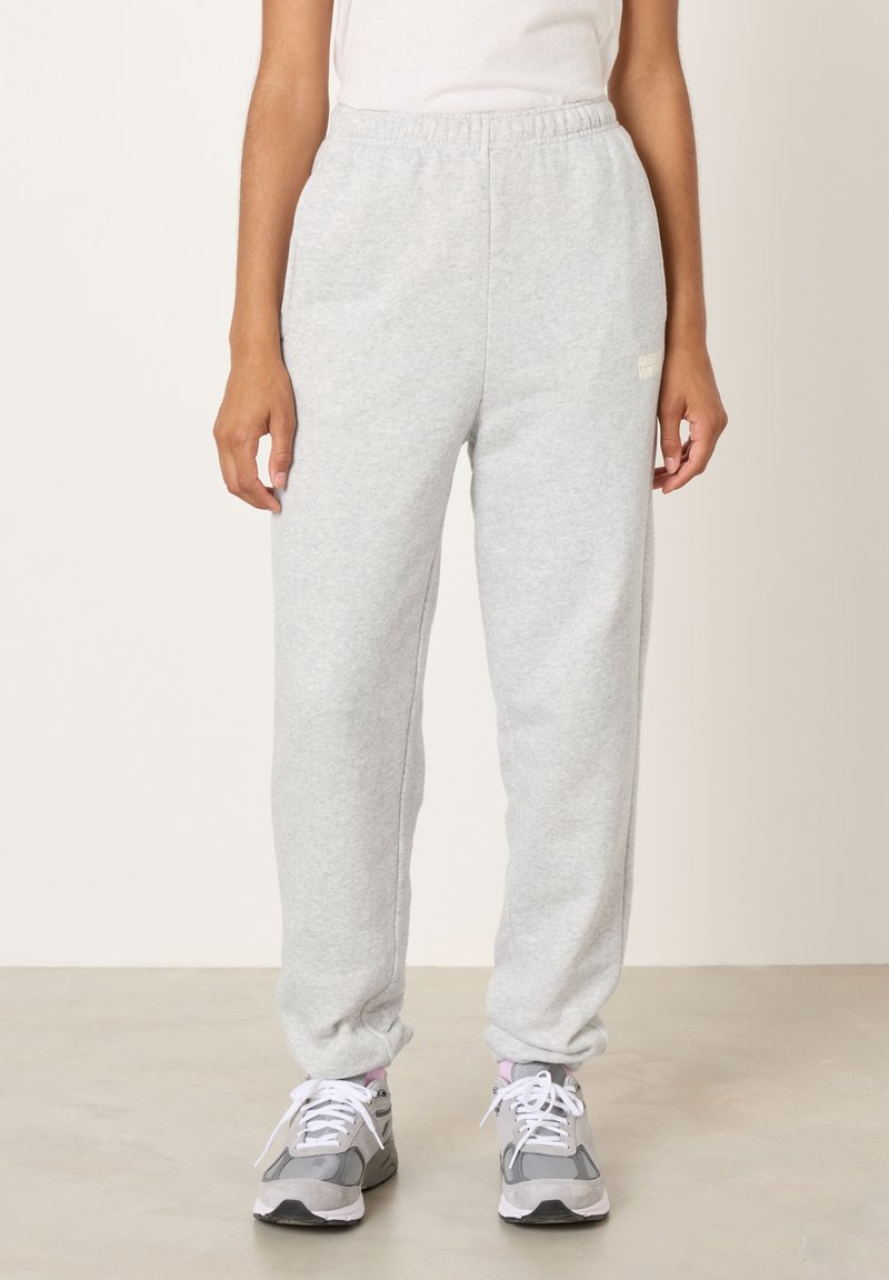 Sivé tepláky s elastickým pásom, zúženými nohavicami a mäkkou, textúrovanou látkou. Na prednej strane je malý logotyp.