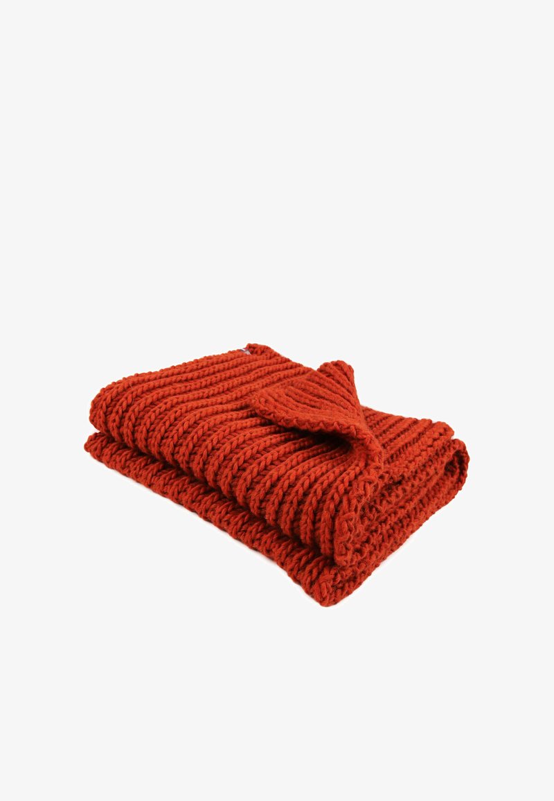 Couverture tricotée en rouge vif avec des côtes texturées et un coin replié, mettant en valeur une construction en laine épaisse.