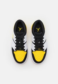 Czarne, białe i żółte buty sportowe z teksturowaną cholewką, perforowanym obszarem palców, płaskimi sznurówkami i wyraźnym logo na języku.