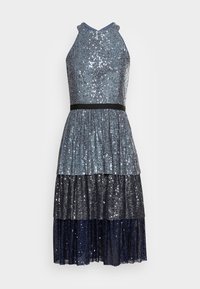 Un vestito con collo allacciato al collo, caratterizzato da paillettes in sfumature di blu, argento e blu notte, con una cintura nera in vita e balze plissettate nella gonna.