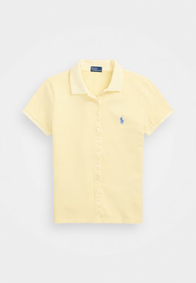Dzeltena īsa piedurkņu polo krekls, kas izgatavots no kokvilnas, ar apkakli, pogu apdari un mazu zilu logo izšuvumu uz krūtīm.