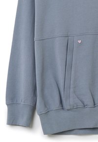 Felpa azzurra chiara con polsini e orlo a costine. Presenta una tasca frontale e un piccolo accento a forma di cuore rosa vicino alla tasca. Tessuto con texture liscia.