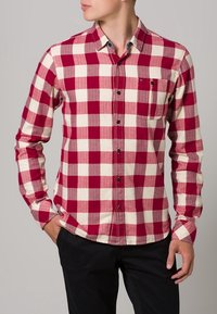 Rood-wit geblokt flanellen shirt met knoopsluiting, kraag, lange mouwen en een borstzak. Heeft een subtiele textuur en knoopaccenten.
