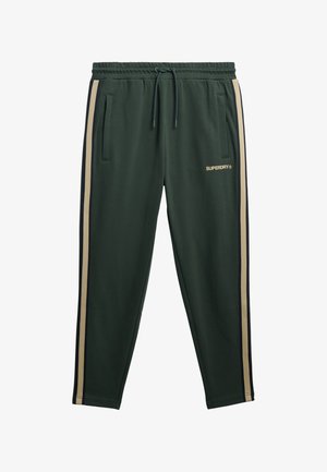 Pantaloni tuta verdi con elastico in vita, cordoncino, tasche laterali e strisce verticali beige e blu navy. Presentano il logo "SUPERDRY" in oro.