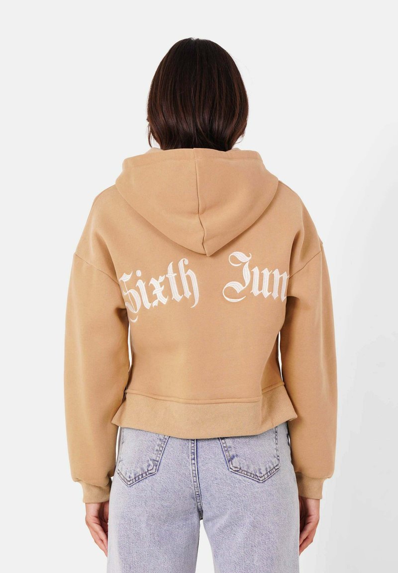 Sudadera corta marrón con capucha, que presenta el texto en blanco "Sixth Jun" en la parte posterior, confeccionada en un tejido suave con un ajuste relajado.