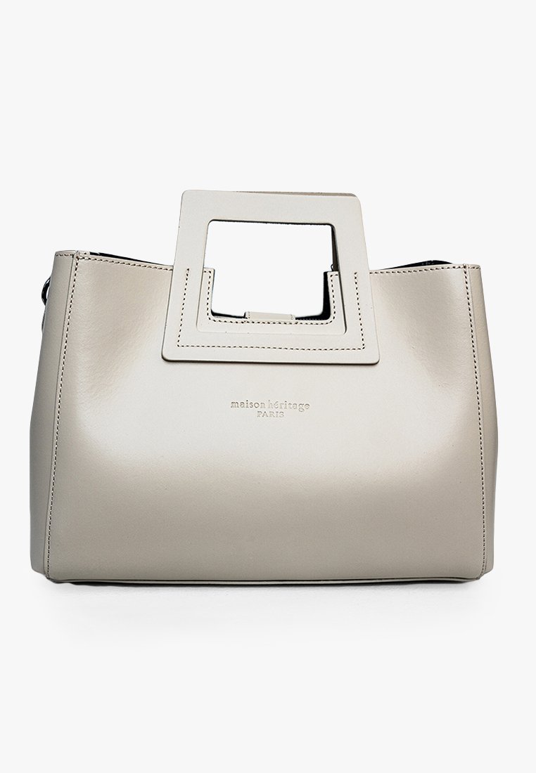 Bolso de mano de cuero beige con un mango recortado angular, diseño estructurado, logotipo grabado en la parte frontal y textura suave.