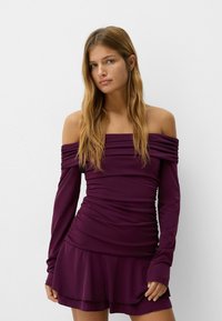 Off-the-shoulder purple dress with long sleeves, ruched fabric throughout, and a flared skirt. Smooth texture and fitted silhouette.