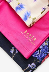 Trzy koszulki: różowa góra, kremowa środkowa z kwiatowym wzorem, granatowa dolna z kwiatowym wzorem, z napisem "BAKER by TED BAKER" w złotym kolorze na różowej koszulce.