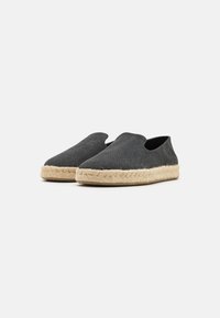 Scarpe slip-on in suede grigio scuro con punta rotonda e suola in corda di juta, caratterizzate da una texture liscia e un design minimalista.