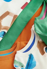 Quatre sweat-shirts pliés de couleurs variées : vert, orange, crème avec des motifs. Présentent des cols côtelés et des coutures surpiquées.
