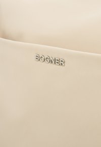 Beige synthetic bag featuring a textured surface with a front pocket, marked by a silver "BOGNER" logo.
