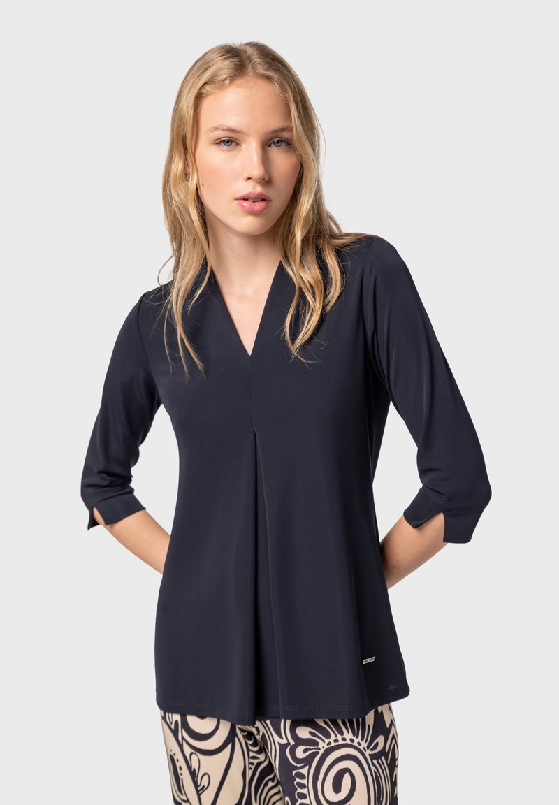 Blusa blu navy con scollo a V, maniche a tre quarti e dettaglio di piega frontale, realizzata in tessuto leggero e morbido.