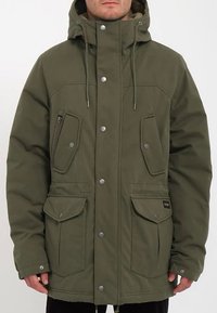 Olive green parka jacket made of textured fabric, featuring a hood, dual chest pockets, and multiple snap buttons for closure.