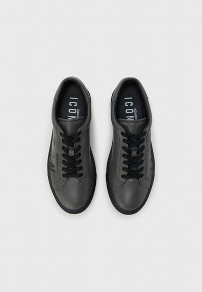 Μαύρα δερμάτινα αθλητικά παπούτσια με υφή στις πλευρές, στρογγυλή μύτη και μαύρα κορδόνια. Φέρουν το όνομα της μάρκας "DSQUARED2" τυπωμένο στο πλάι.