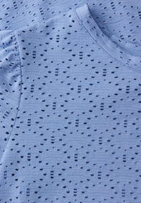 Lichtblauwe gebreide stof met kleine, gelijkmatig verspreide gaatjes en subtiele horizontale ribbels, met een afgeronde halslijn en een geplooide mouwdetail.