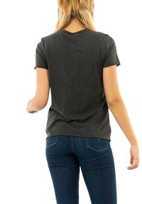 Camiseta de manga corta gris oscuro en una suave mezcla de algodón con un corte relajado y un escote redondeado, llevada con unos vaqueros azules.