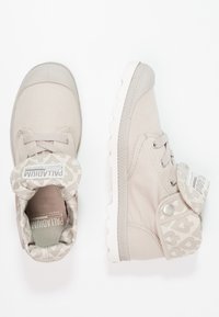 Scarpe high-top in tessuto beige con collare imbottito, suola in gomma testurizzata e accenti beige a fantasia. Presentano lacci e chiusura a pressione.