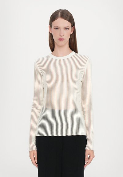 Long-sleeve, sheer top with vertical stripes in white and light beige, featuring a round neckline and fitted texture, worn with black pants.